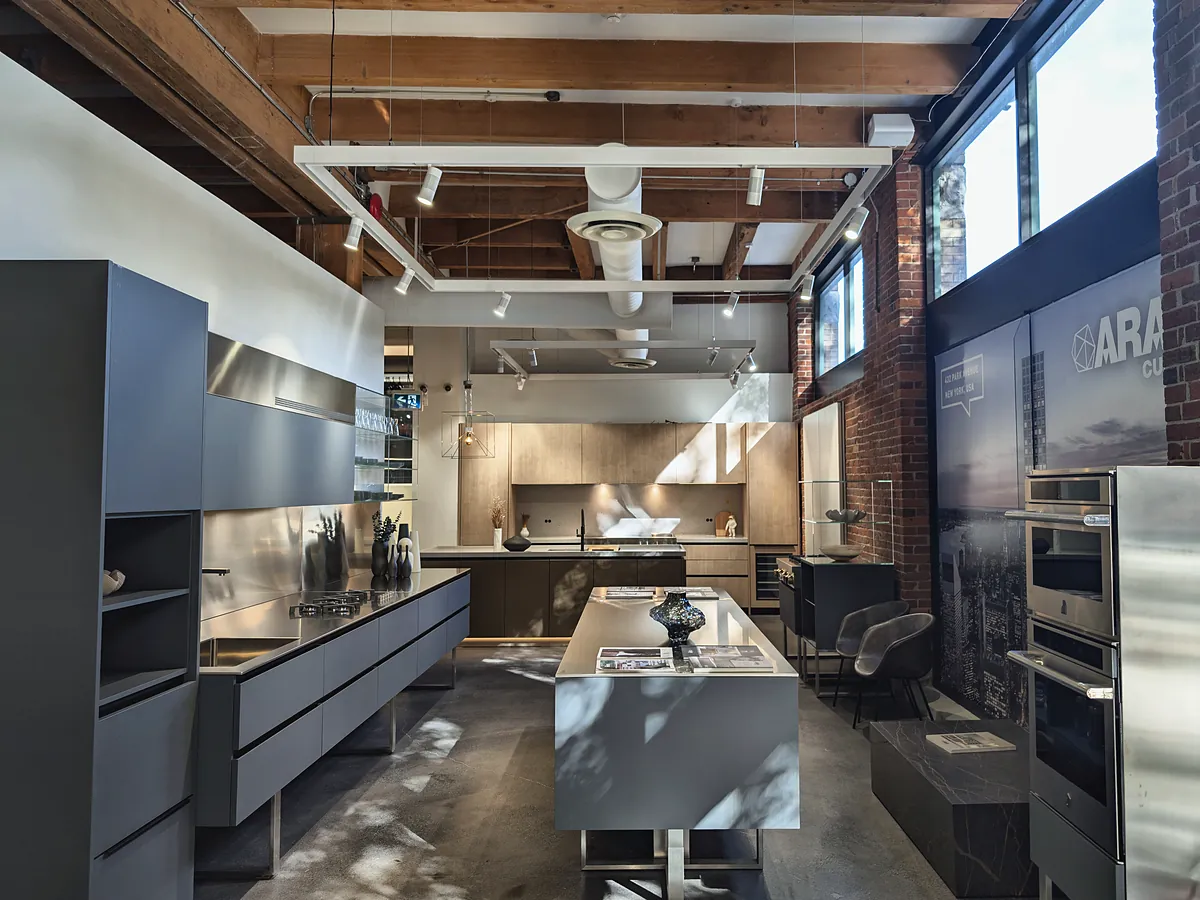 The showroom floor: finished kitchens, a brick wall with tall windows and exposed timber beams overhead.